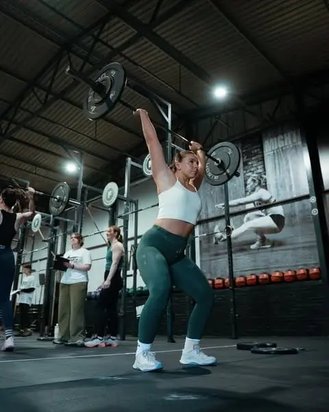 Member holding a barbell overhead at Mighty Fitness, Durham